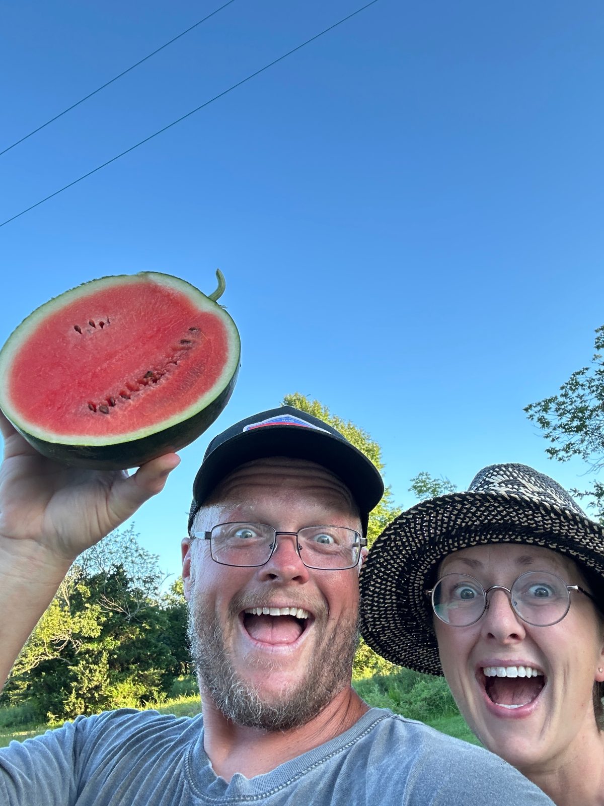 Cas and Sarah holding up a halved watermelon, laughing
